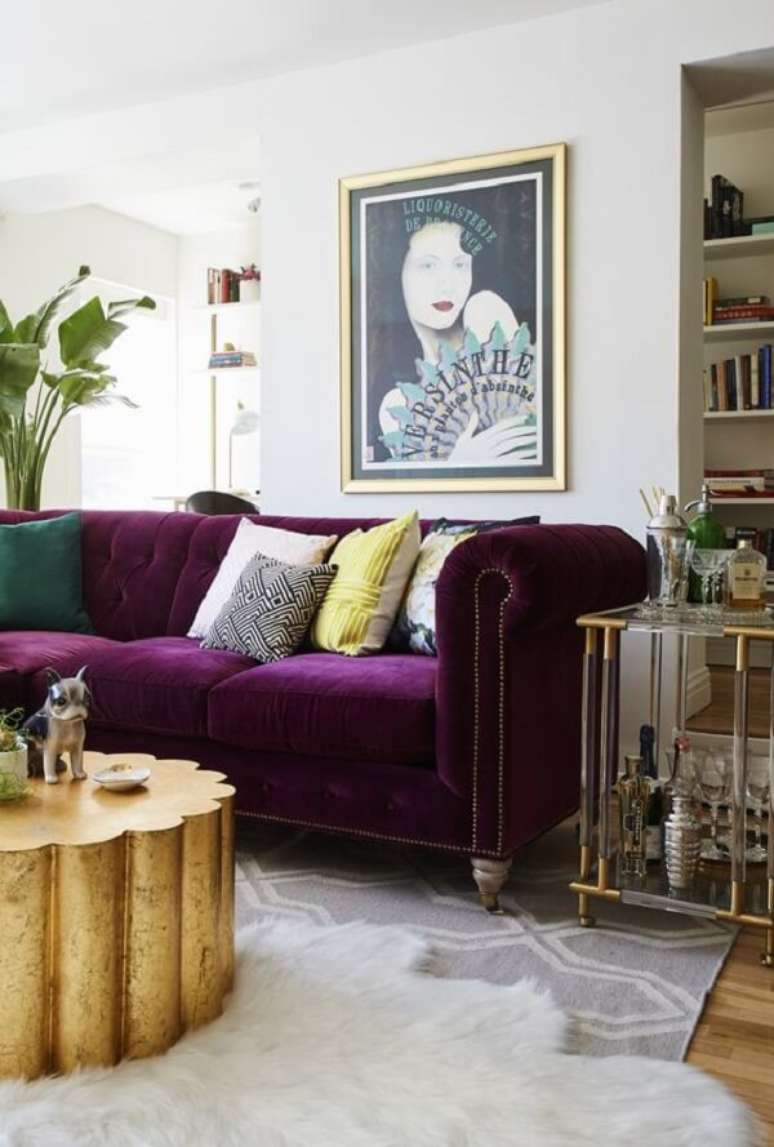 3. O sofá roxo escuro quebra a neutralidade da decoração desse ambiente. Fonte: Domino Magazine