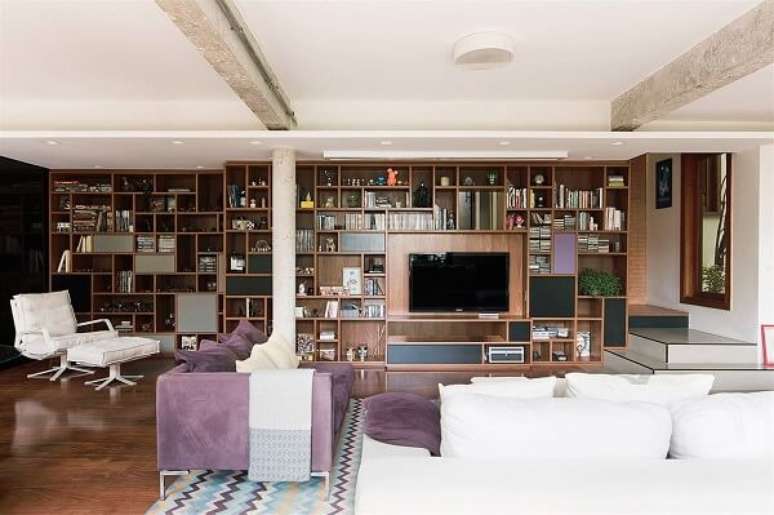 4. O tapete com estampa geométrica apresenta nuances em roxo conversando diretamente com o sofá roxo do local. Projeto por A.M Studio Arquitetura