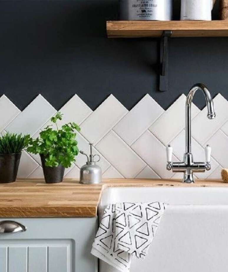 20. Revestimento cer&acirc;mico branco para decora&ccedil;&atilde;o de cozinha com parede azul escura e bancada de madeira &ndash; Foto: Casa Montada