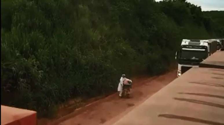 Sem acostamento, o profissional fica parado diante do movimento das carretas, em fila tripla