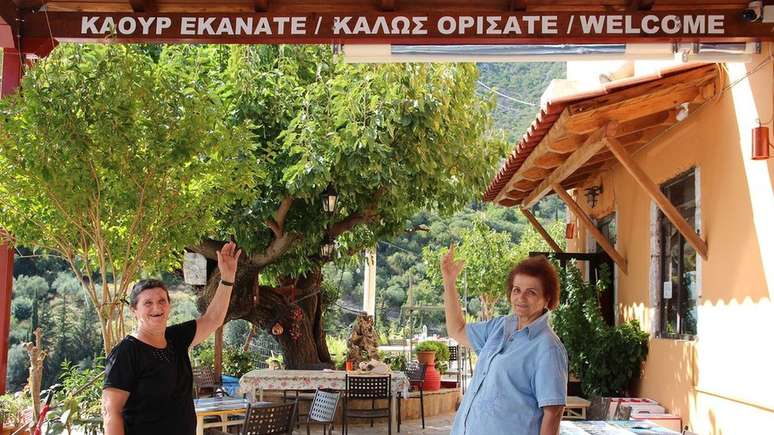 Placas em tsakoniano e grego moderno dão as boas-vindas aos visitantes no vilarejo de Pera Melana