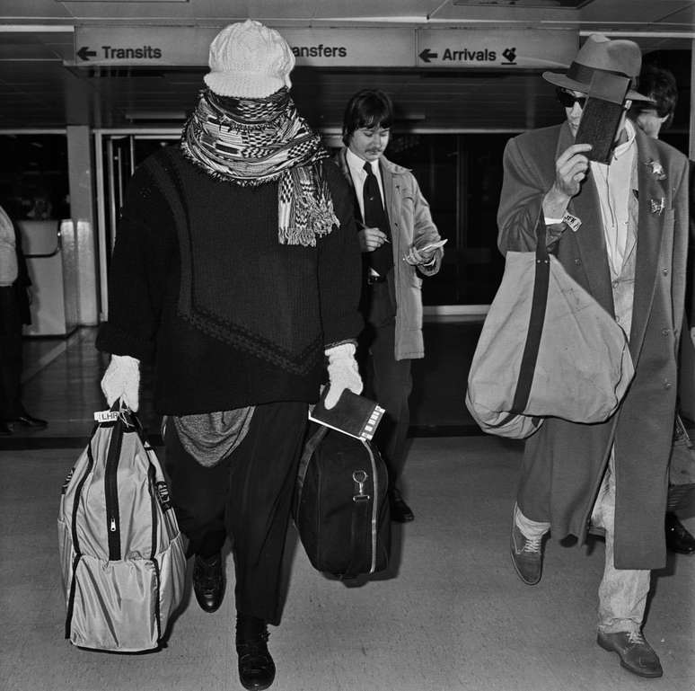 Cantor Boy George chega ao aeroporto de Heathrow em 1985, disfar&ccedil;ando-se com um len&ccedil;o