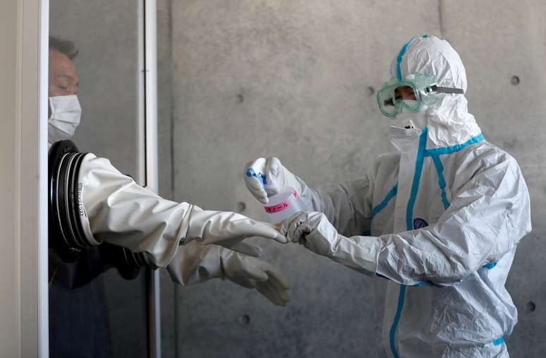 Profissional de saúde desinfecta luvas de colega em Tosuka, ao sul de Tóquio
23/02/2020 REUTERS/Issei Kato