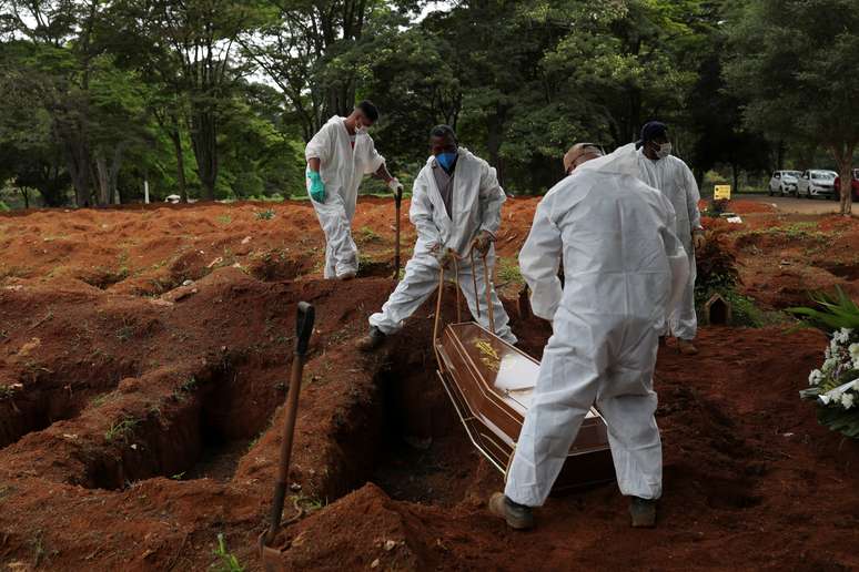 Coveiros vestindo traje de proteção enterram homem que morreu de Covid-19, no cemitério de Vila Formosa, em São Paulo
25/12/2020
REUTERS/Amanda Perobelli