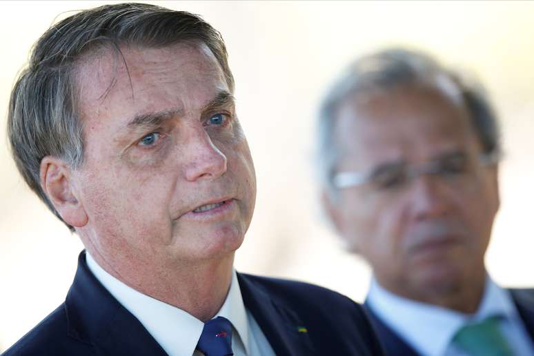 O ministro da Economia, Paulo Guedes, observa o presidente da República, Jair Bolsonaro. 27/04/2020. REUTERS/Ueslei Marcelino. 

