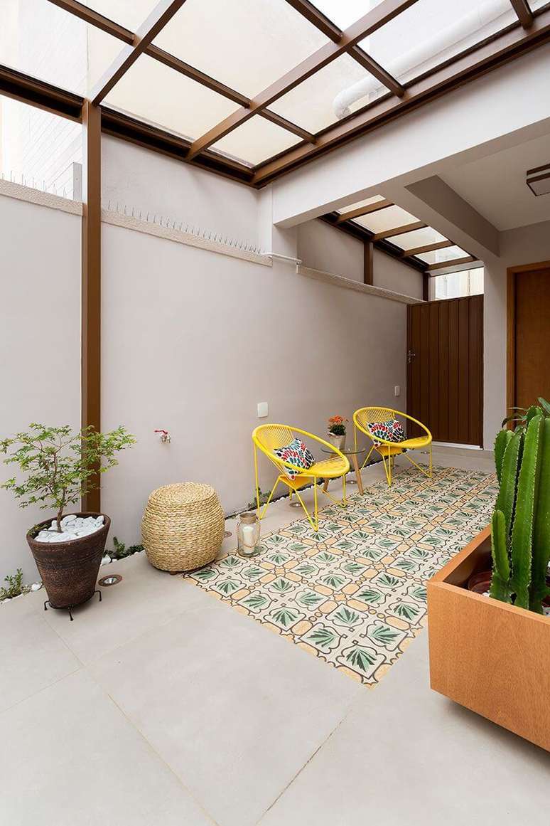 2. Terraço aconchegante com cadeira acapulco e piso de azulejo antigo colorido. Projeto por Juliana Conforto