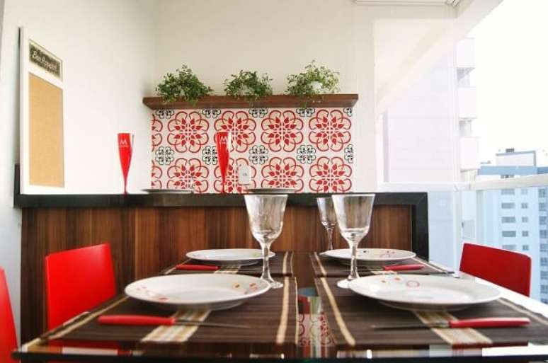 12. Varanda com parede de azulejos antigos com nuances em vermelho se conectam com as cadeiras da mesa. Projeto Por Priscila Fernandes Arquitetura