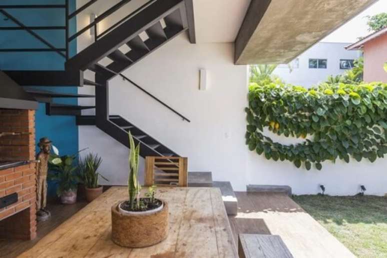 8. O revestimento para escada em ferro se conecta com a com churrasqueira tradicional em tijolos e demais elementos madeira. Fonte: Cawy Arquitetura e Constru&ccedil;&atilde;o