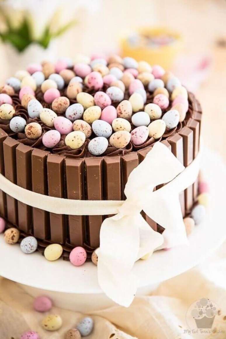 16. Modelo de bolo de Páscoa decorado com ovinhos coloridos e barrinhas de chocolate em volta – Foto: Pinterest