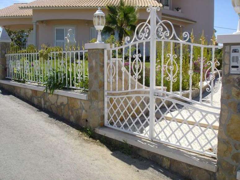 23. Port&atilde;o de ferro baixo e bem trabalhado em casa com jardim na frente. Foto de Cell Code