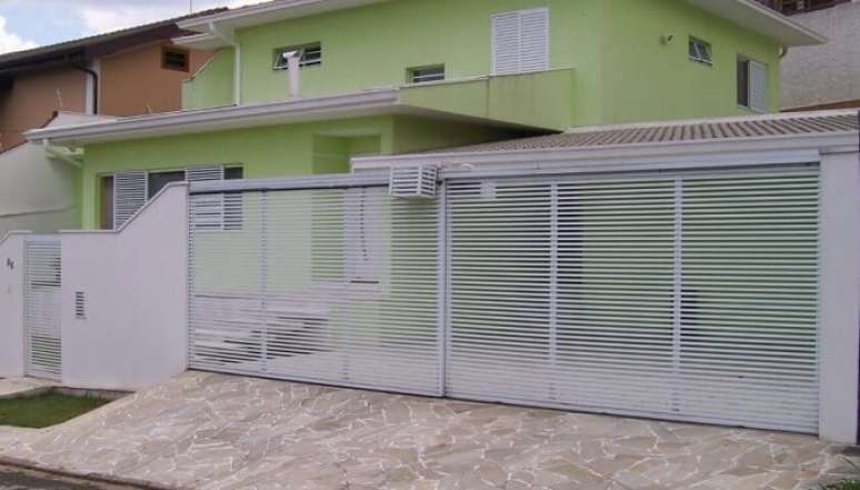 21. Port&atilde;o de ferro branco em casa verde. Foto de Banfer