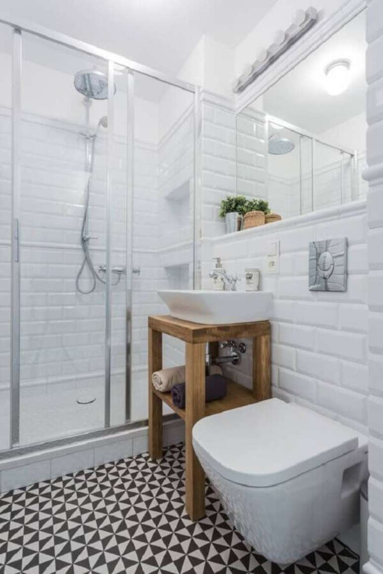 7. Azulejo de banheiro simples decorado com piso preto e branco e armário pequeno de madeira. Foto: Homify