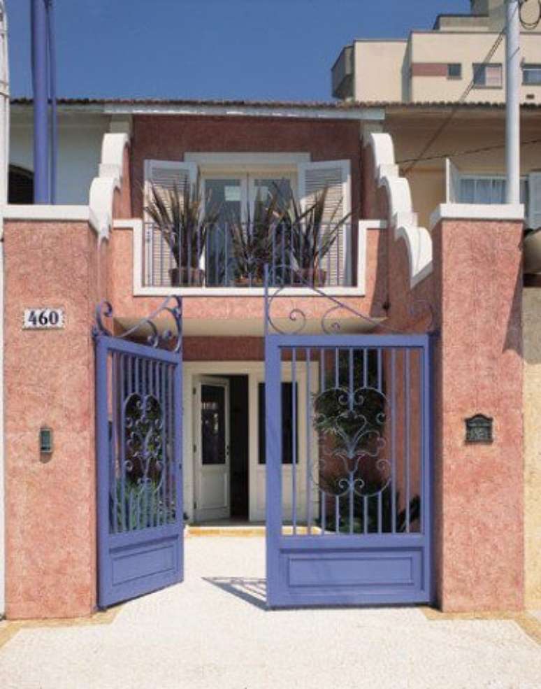 27. Port&atilde;o de ferro roxo em casa com fachada em tom rosa. Foto de EMD Battery