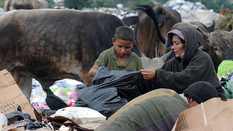690 milhões de pessoas passaram fome em 2019, de acordo com a FAO. Na foto, uma mulher e uma criança procuram comida no meio do lixo