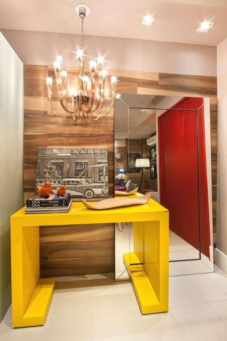 29. O aparador amarelo com espelho de chão decoram o hall de entrada do imóvel. Fonte: Gerson Dutra de Sá e Ana Lucia Salama