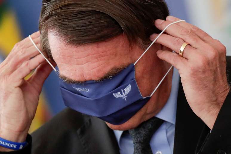 Presidente Jair Bolsonaro tenta colocar m&aacute;scara durante evento no Pal&aacute;cio do Planalto
22/03/2021
REUTERS/Ueslei Marcelino