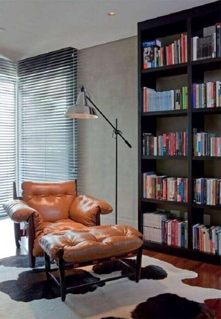 34. Decoração de cantinho de leitura com confortável poltrona marrom e estante de livros preta – Foto: Pinterest
