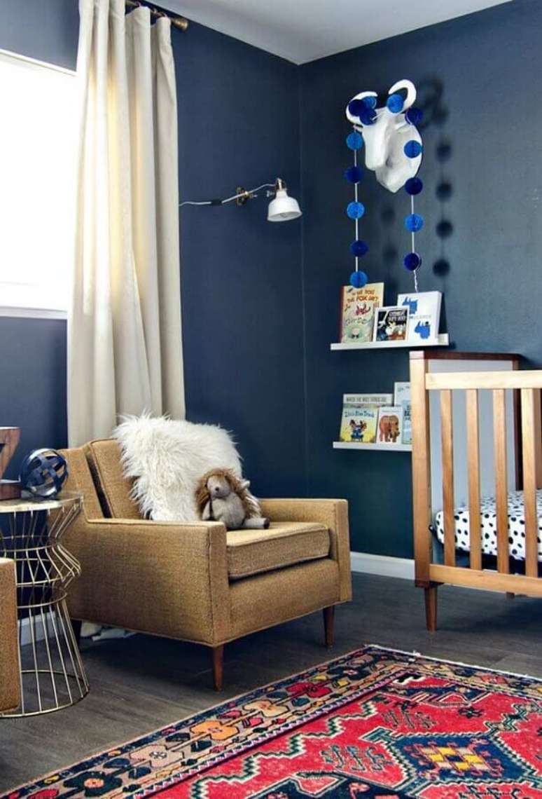 63. Quarto de bebê azul marinho decorado com berço de madeira e poltrona de amamentação – Foto: Pinterest