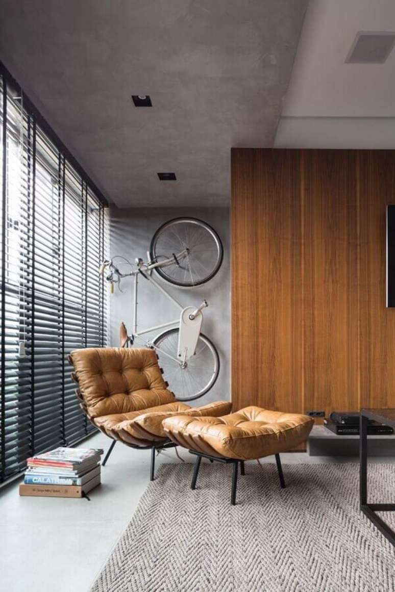 13. Decoração estilo industrial com parede de cimento queimado e poltrona marrom confortável – Foto: Futurist Architecture