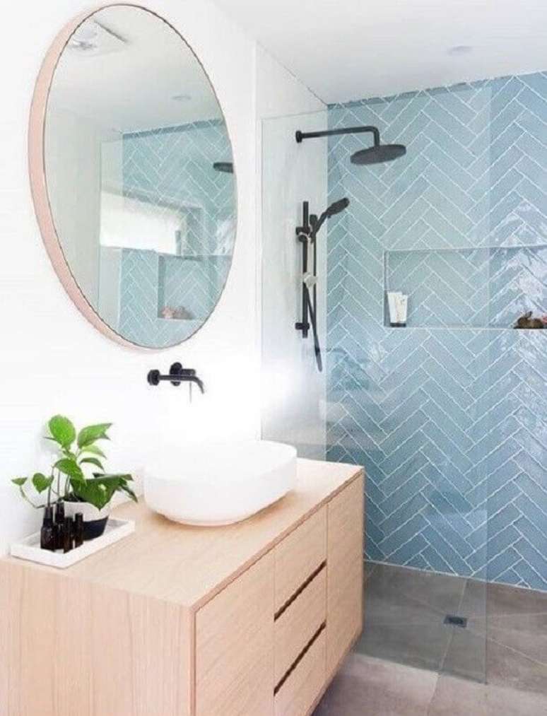 49. Gabinete de madeira clara para decoração de banheiro azul e branco com espelho redondo – Foto: Micasa Revista