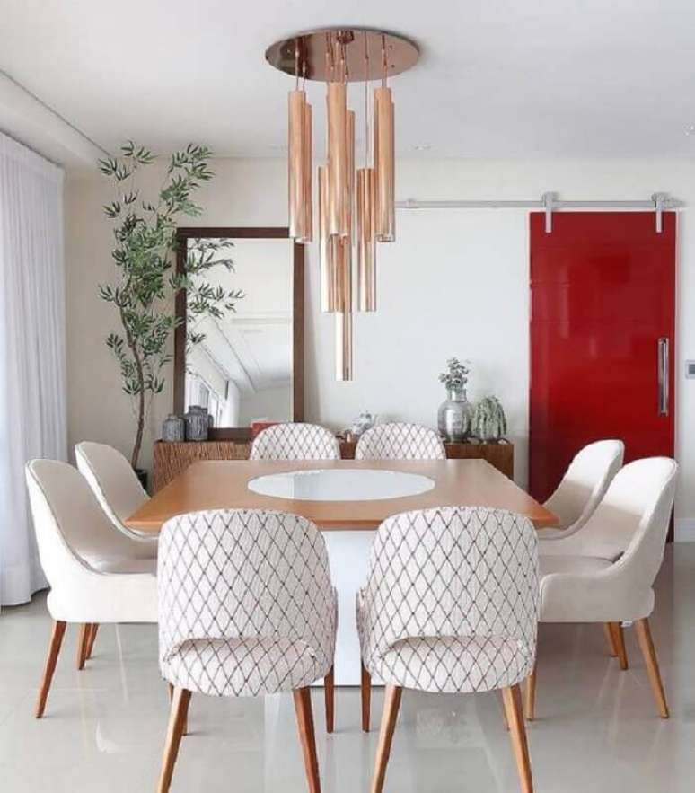 48. Cadeiras acolchoadas para mesa de jantar quadrada decorada com lustre moderno rose gold – Foto: Dicas de Mulheres