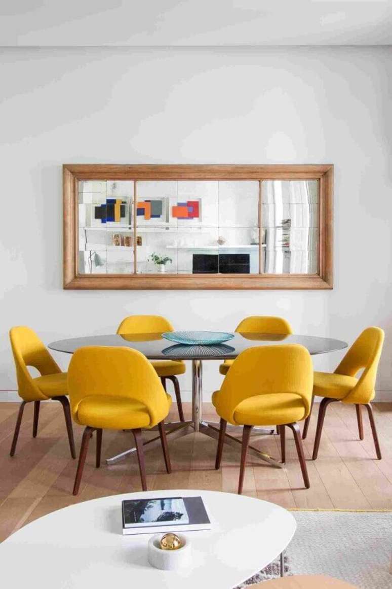 59. Decoração de sala de jantar com espelho de parede e cadeiras acolchoadas amarelas – Foto: Behance