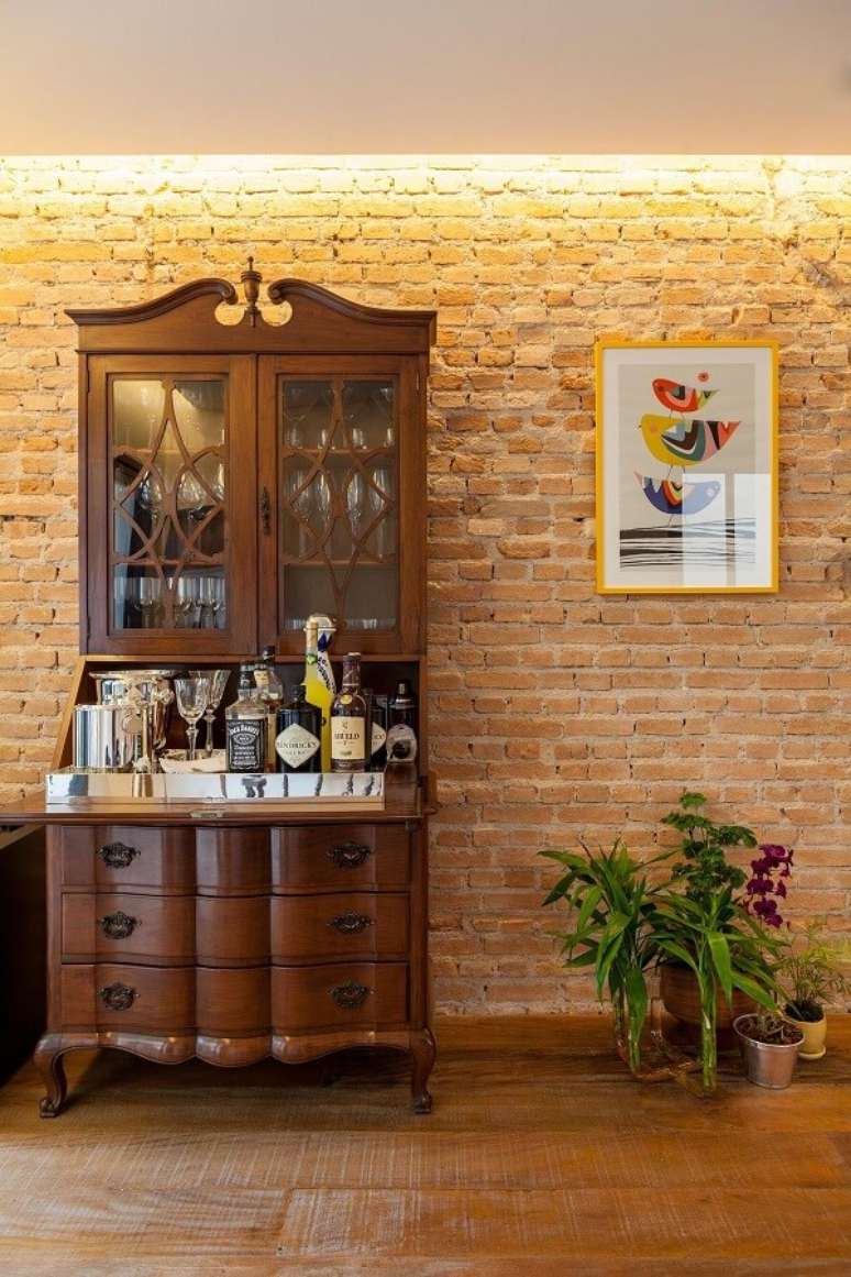 44. A estrutura da cristaleira r&uacute;stica foi usada para a cria&ccedil;&atilde;o de um mini bar na sala. Fonte: Tria Arquitetura