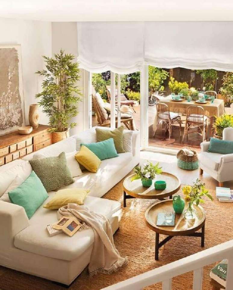 55. Mesa de centro redonda de madeira para sala de estar decorada com almofadas coloridas – Foto: Jeito de Casa