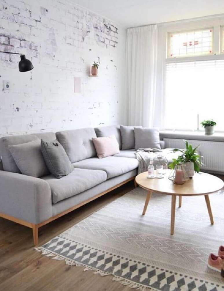 56. Sala minimalista decorada com sof&aacute; cinza claro e mesa de centro redonda de madeira &ndash; Foto: Casa de Valentina