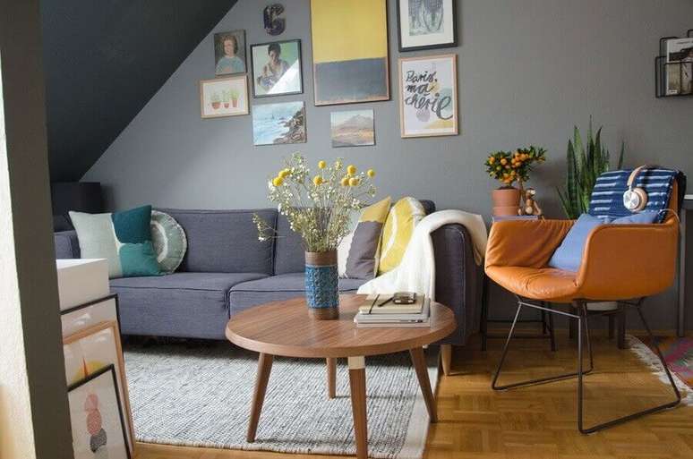 5. Mesa de centro redonda de madeira para sala cinza decorada com poltrona de couro marrom – Foto: Houzz