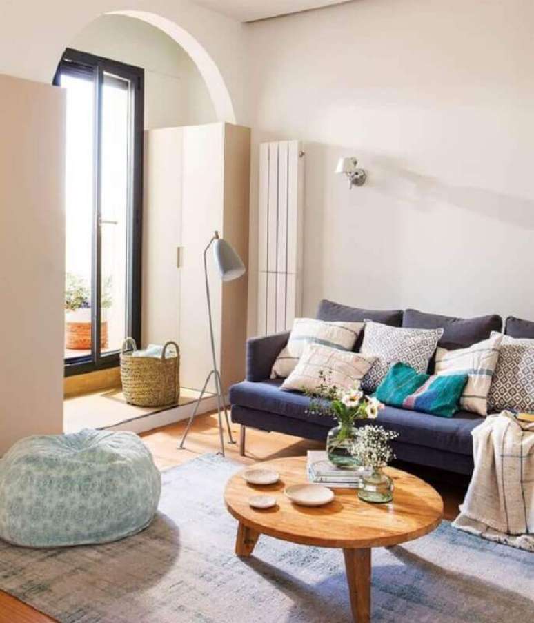 59. Sala simples decorada com mesa de centro redonda de madeira e sofá azul marinho – Foto: El Mueble