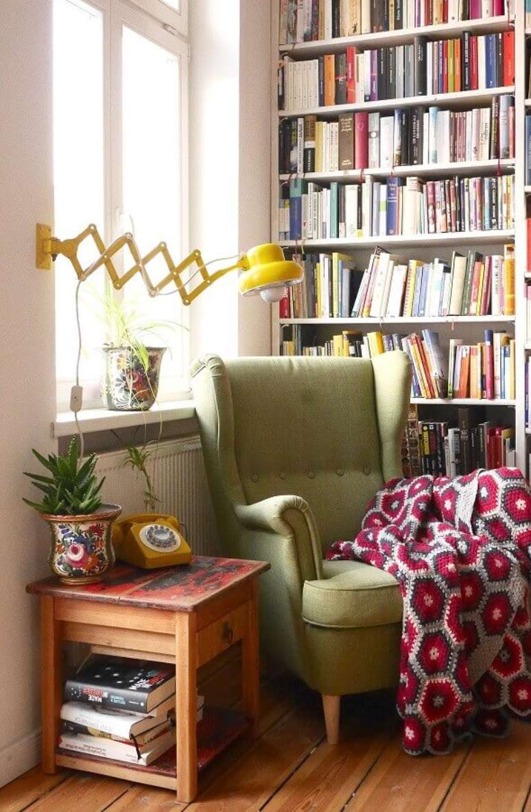 14. Luminária de parede para leitura em cantinho decorado com estante de livros e poltrona verde – Foto: Pinterest