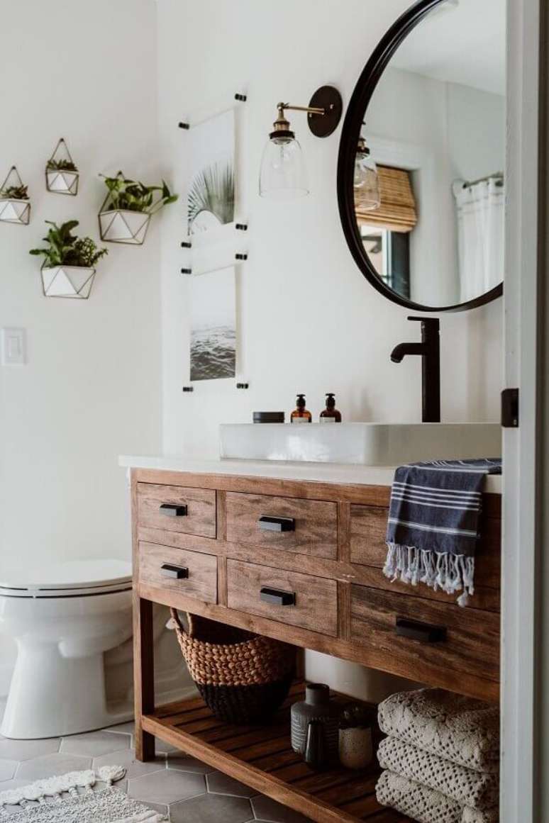 21. Luminária de parede de vidro para decoração de banheiro com gabinete de madeira e espelho redondo – Foto: Decoholic