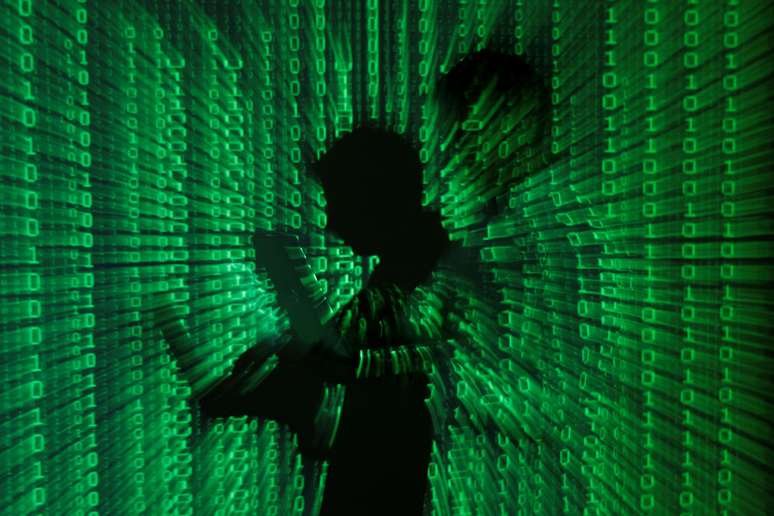 Ilustração mostra projeção de códigos binários com homem no centro segurando um laptop. 24/6/2013. REUTERS/Kacper Pempel