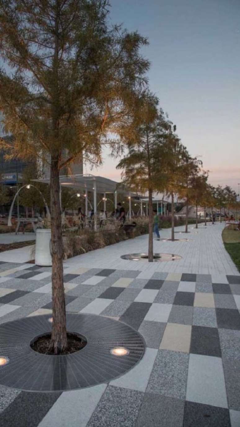 12. Piso intertravado colorido em tons neutros decoram a &aacute;rea externa com canteiros com &aacute;rvores. Fonte: Pinterest