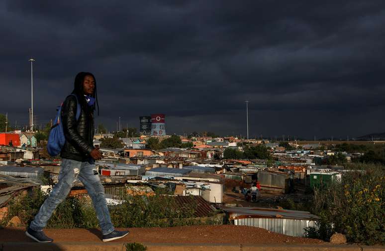 Homem passa por um assentamento informal enquanto restrições à mobilidade são amenizadas no Soweto, África do Sul. 7 de abril de 2021. REUTERS/Siphiwe Sibeko