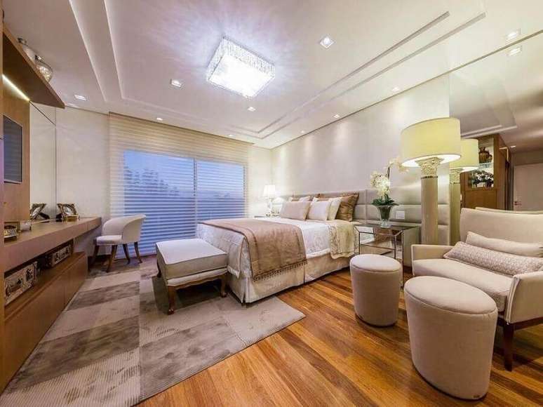 28. Decora&ccedil;&atilde;o de quarto bege amplo com poltrona confort&aacute;vel e painel para TV &ndash; Foto: Pinterest