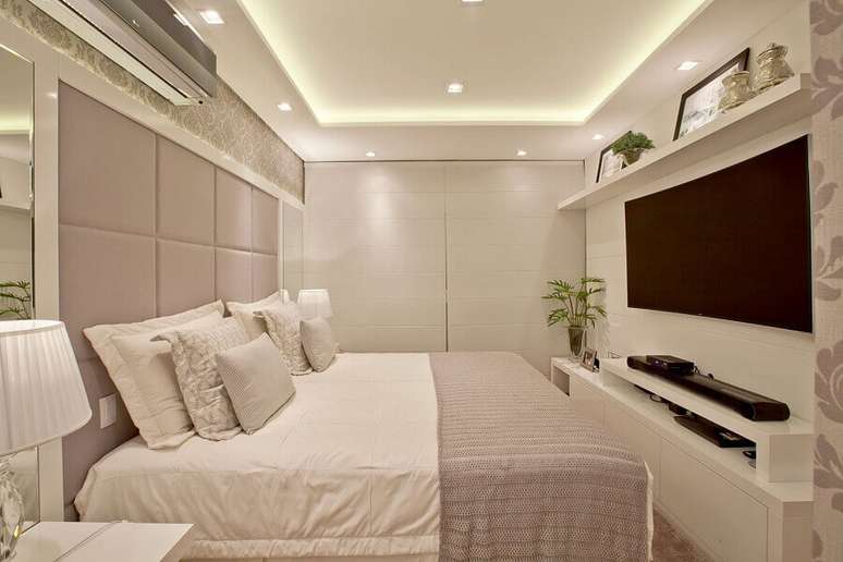 24. Decoração de quarto de casal bege e branco com painel de TV – Foto: Arq MBaptista