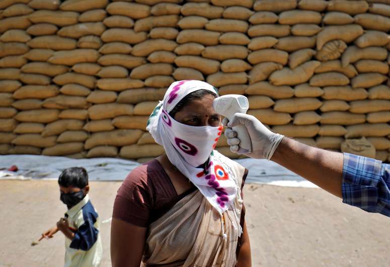 Profissional de saúde checa temperatura de funcionária de unidade beneficiadora de arroz na vila de Bavla, nos arredores de Ahmedabad, na Índia
13/04/2021 REUTERS/Amit Dave