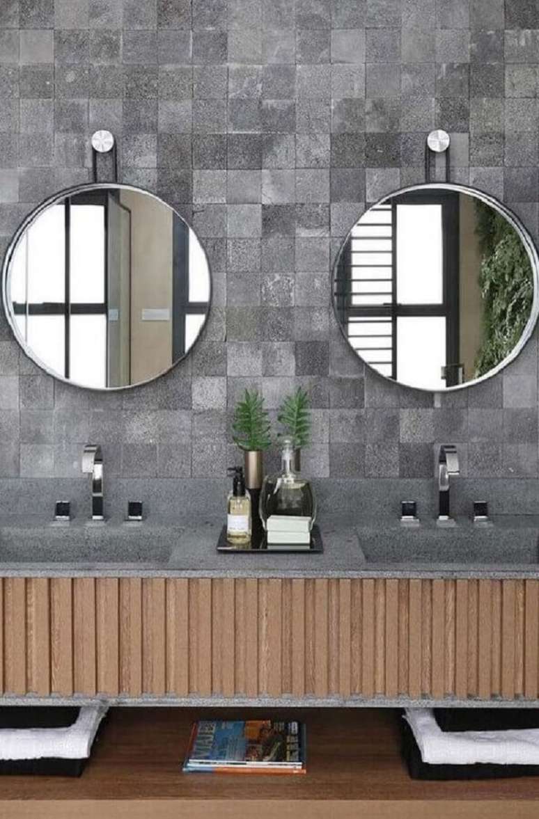 28. Decoração de banheiro com revestimento cinza e espelho redondo – Foto: Quattrino Arquitetura
