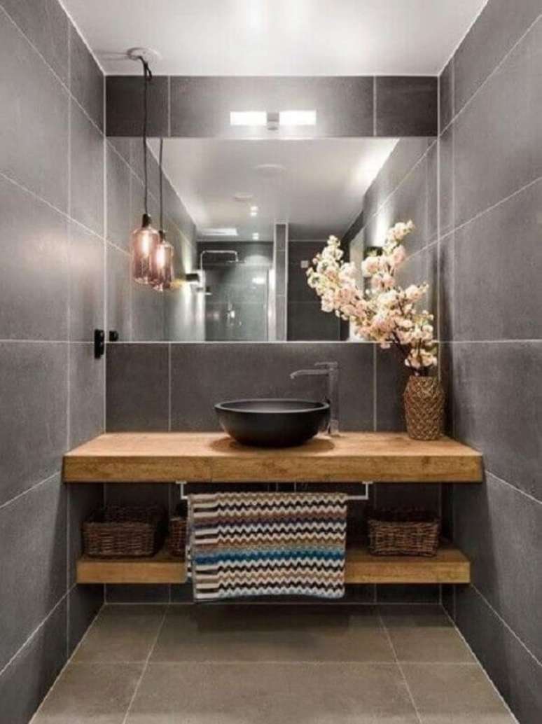 51. Revestimento cinza para banheiro pequeno decorado com bancada de madeira e cuba preta – Foto: Freshideen