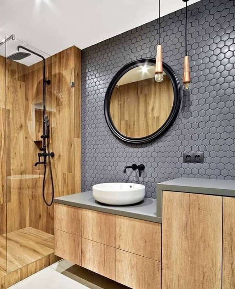 26. Banheiro amadeirado moderno decorado com espelho redondo e revestimento hexagonal cinza – Foto: Jeito de Casa
