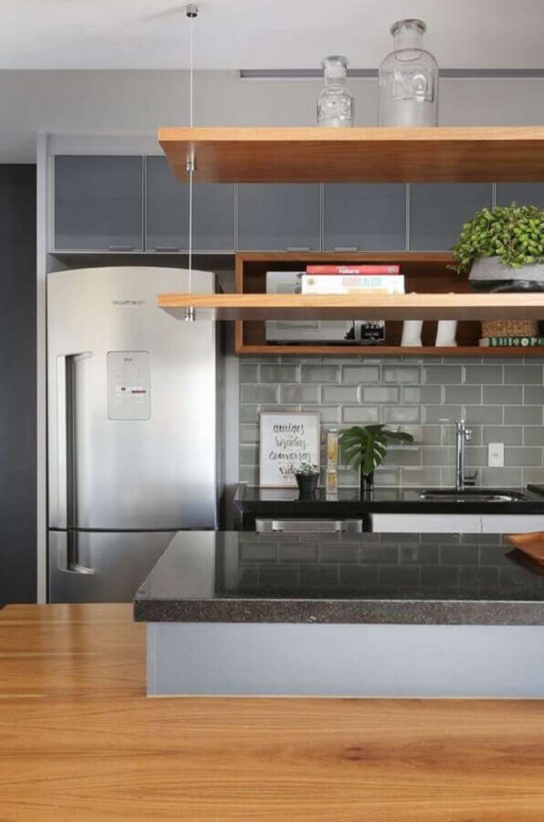 33. Revestimento metro cinza para decoração de cozinha planejada com prateleira suspensa de madeira – Foto: Jeito de Casa