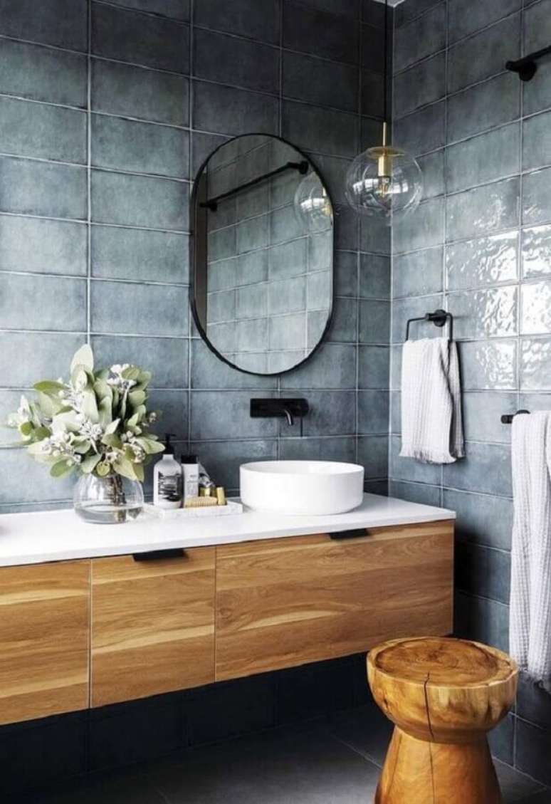 17. Revestimento cinza par banheiro moderno decorado com gabinete de madeira e espelho oval – Foto: Freshideen