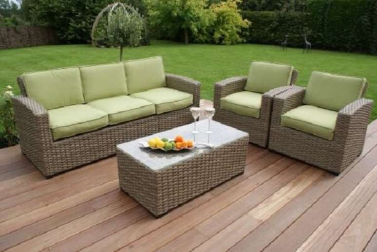 18. As almofadas em tom verde do sof&aacute; de vime se misturam com a grama do jardim. Fonte: Pinterest