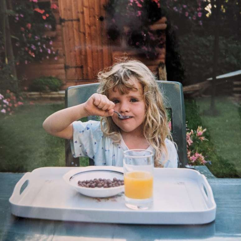 Loretta ainda criança comendo café da manhã de Mavis no jardim
