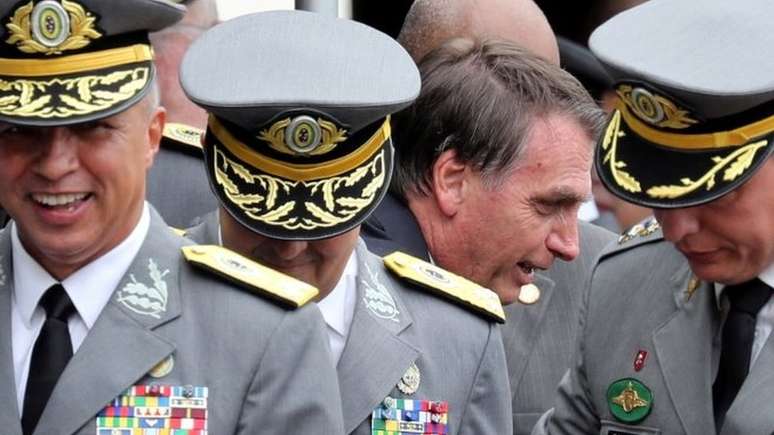 Bolsonaro em cerimônia militar de 2018; "Bolsonaro tem muito apoio nos militares, particularmente nos militares de baixa patente. Por isto muitos ficaram preocupados quando ele demitiu o ministro da Defesa (Fernando Azevedo e Silva) e depois demitiu os chefes das três forças. Bolsonaro também questionou se as eleições do ano que vem serão feitas de maneira justa e livre, como Trump fez em meu país", argumenta Bremmer