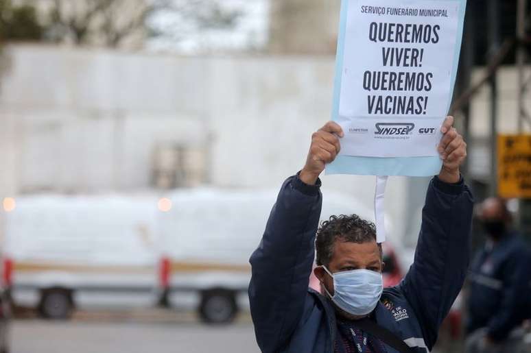 Trabalhador do serviço funerário protesta com cartaz em meio à pandemia da Cvodi-19, em São Paulo. 15/4/2021. REUTERS/Carla Carniel