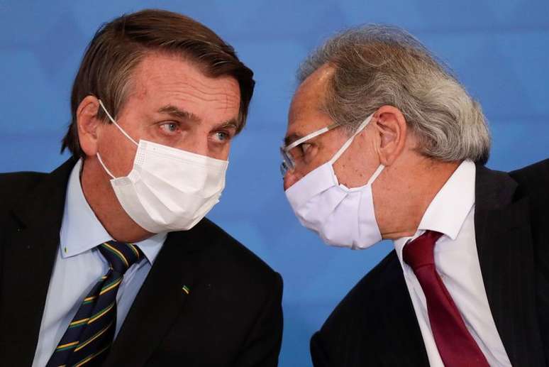 Presidente Jair Bolsonaro fala com o ministro da Economia, Paulo Guedes, durante cerimônia em Brasília. 25/3/2021. REUTERS/Ueslei Marcelino