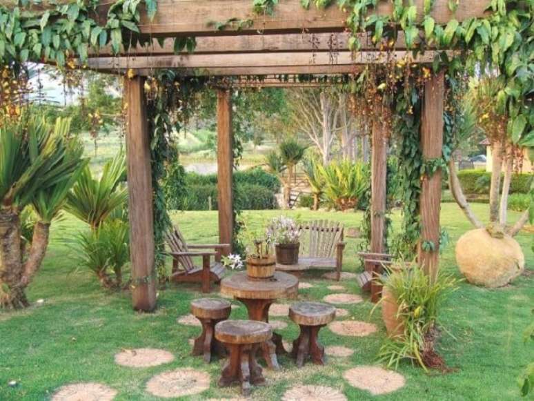 80. Crie um ambiente especial no jardim da casa de fazenda com pergolado e móveis de madeira. Fonte: Pinterest